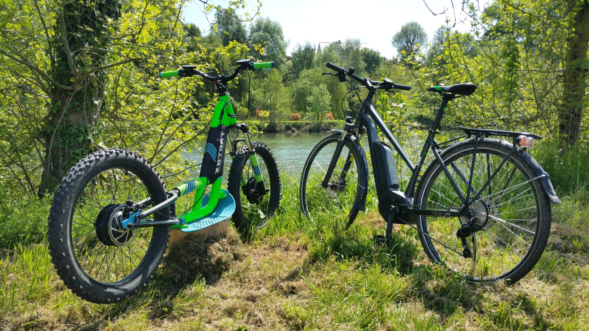 Vélos électriques près d'une rivière ensoleillée.